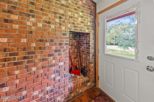 doorway to outside featuring dark wood-style floors and brick wall