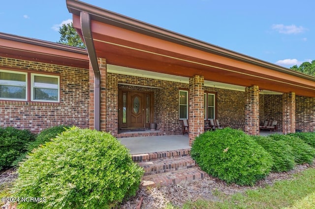 property entrance featuring covered porch and brick siding