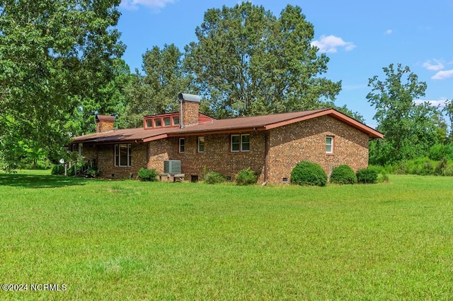 rear view of house featuring crawl space, a chimney, a lawn, and brick siding