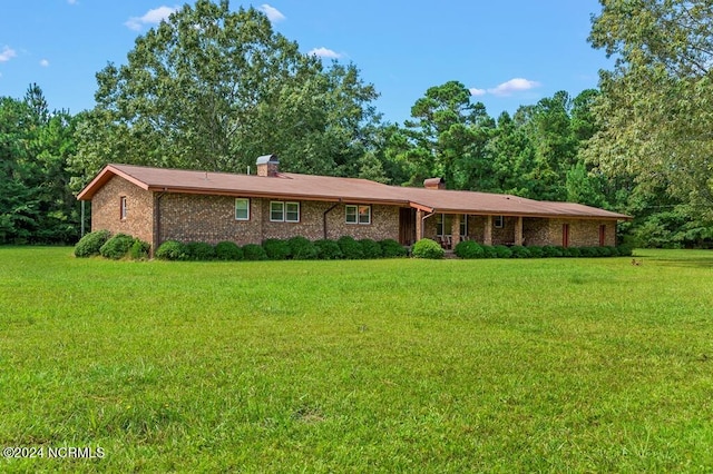 ranch-style home with brick siding, a chimney, and a front yard