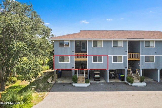 view of property with a carport, aphalt driveway, and an attached garage