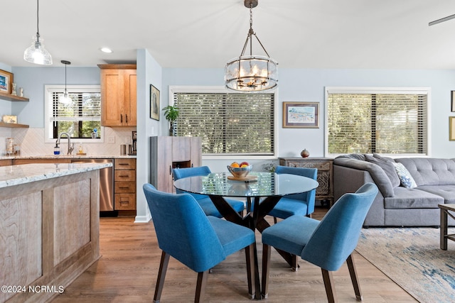 dining space with a notable chandelier, light hardwood / wood-style floors, a healthy amount of sunlight, and sink