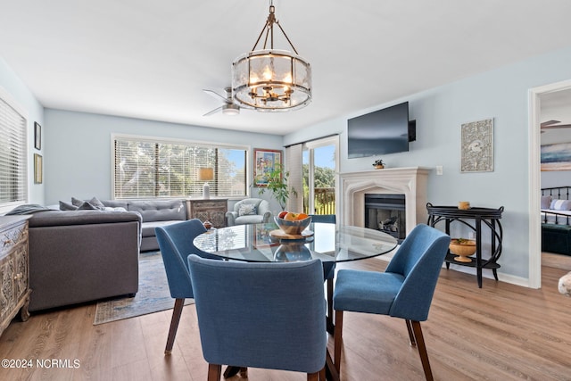 dining space with a glass covered fireplace, baseboards, an inviting chandelier, and wood finished floors