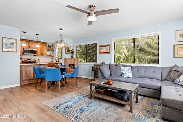 living room with ceiling fan, light wood-style flooring, and baseboards