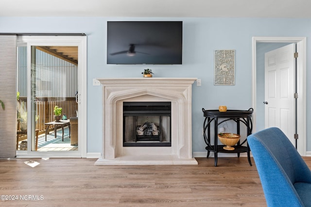 interior details featuring a fireplace with raised hearth, wood finished floors, and baseboards