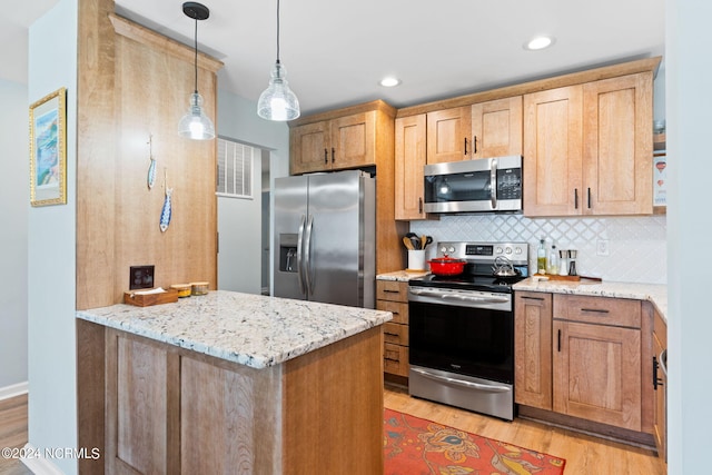 kitchen featuring light stone counters, pendant lighting, decorative backsplash, appliances with stainless steel finishes, and light wood-type flooring