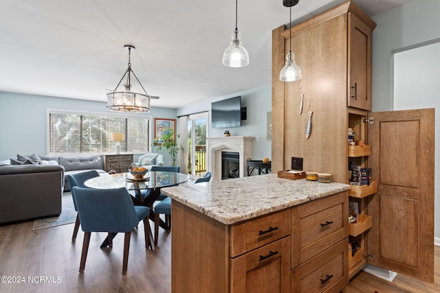 kitchen with a chandelier, pendant lighting, light stone counters, and dark wood-type flooring