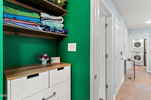 corridor featuring stacked washer / dryer and light hardwood / wood-style flooring