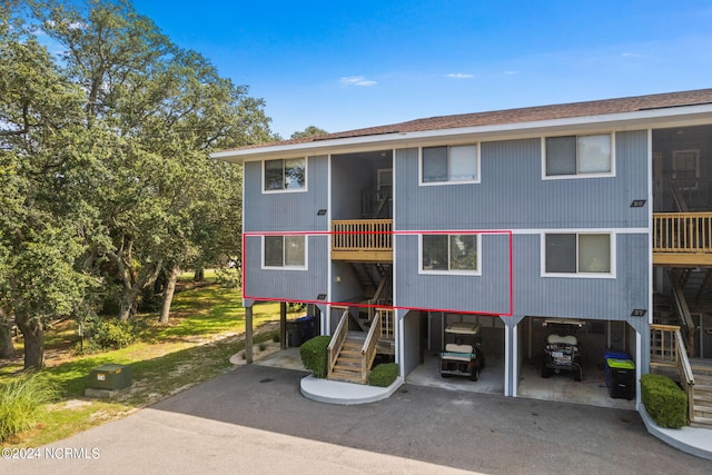 exterior space featuring a carport, stairway, roof with shingles, and driveway