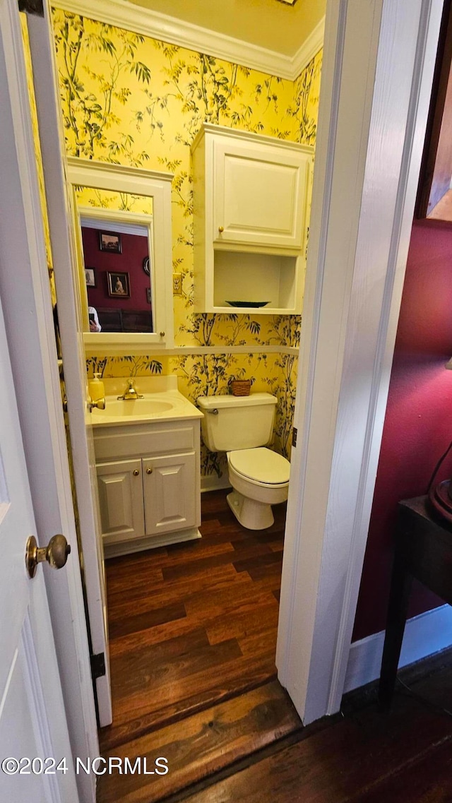 bathroom with wood-type flooring, crown molding, vanity, and toilet