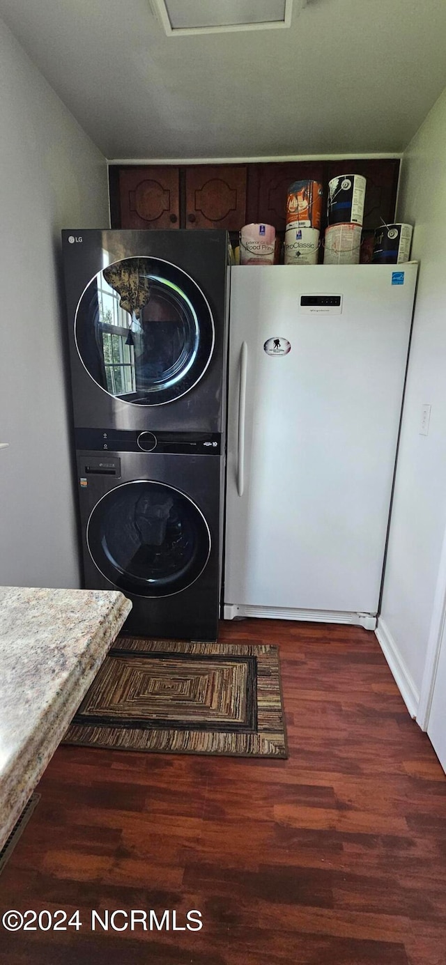 laundry area with dark hardwood / wood-style floors and stacked washer / drying machine