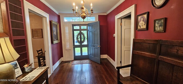 foyer entrance with ornamental molding, a chandelier, and dark wood-type flooring