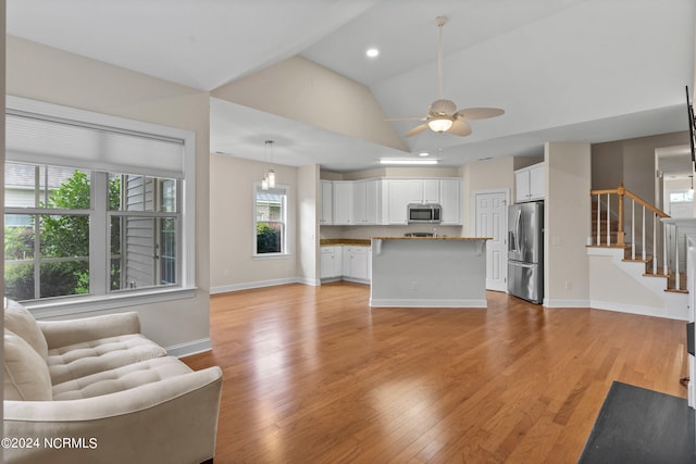 unfurnished living room featuring vaulted ceiling, light hardwood / wood-style flooring, and ceiling fan