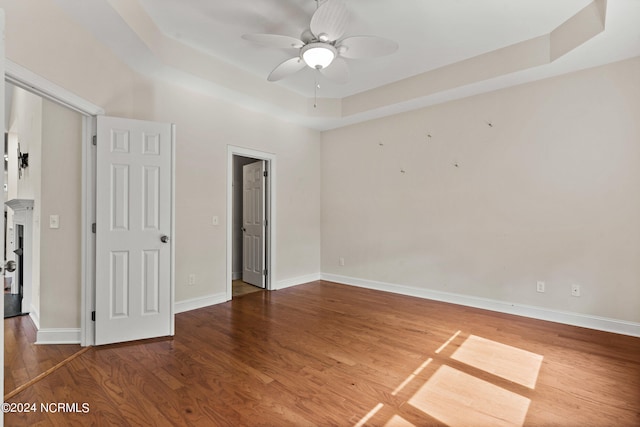 unfurnished room with hardwood / wood-style floors, a tray ceiling, and ceiling fan