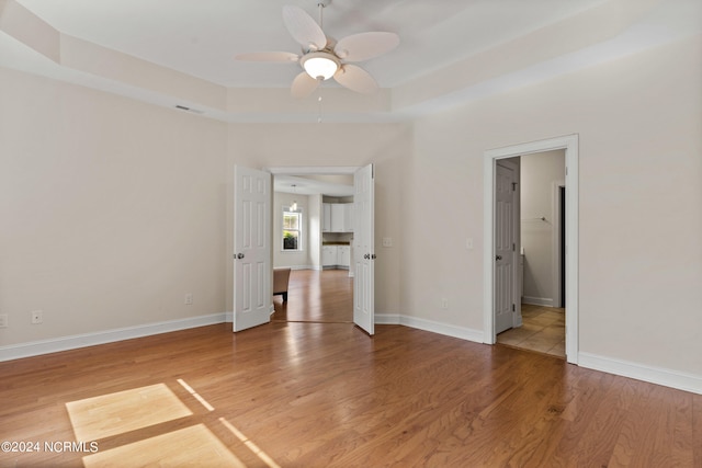 spare room featuring ceiling fan, hardwood / wood-style flooring, and a tray ceiling