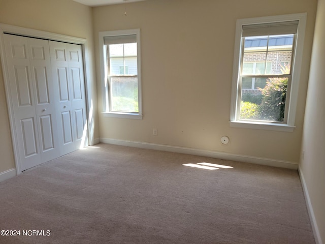 unfurnished bedroom featuring a closet, light carpet, and multiple windows