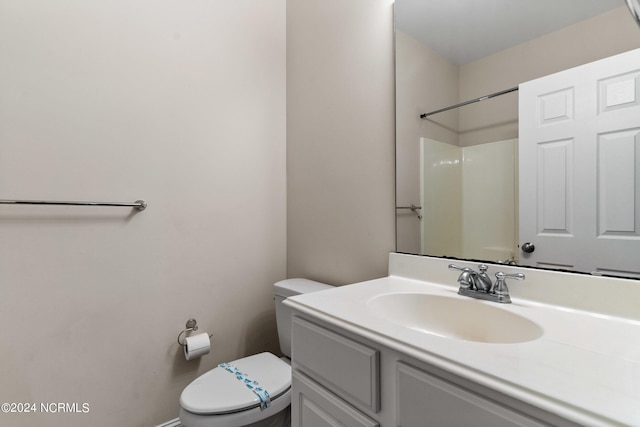 bathroom with toilet, vanity, and a shower