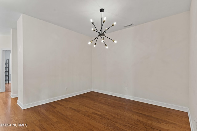 unfurnished room featuring hardwood / wood-style floors and an inviting chandelier