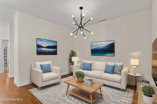 living room featuring wood-type flooring and an inviting chandelier