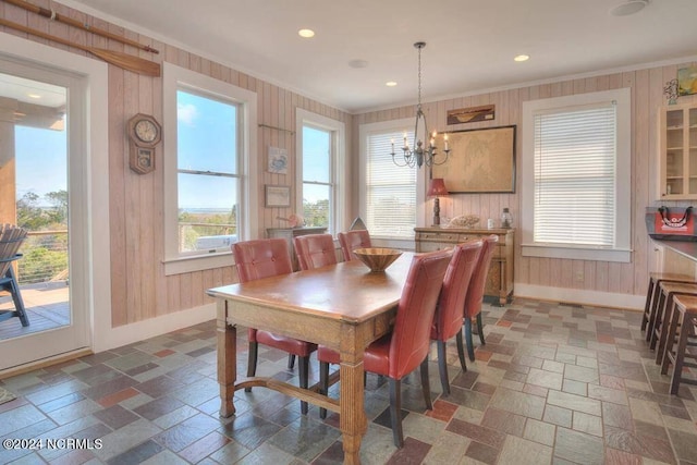 dining space with a notable chandelier, wood walls, and dark tile patterned flooring