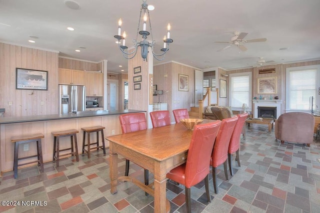 tiled dining area with ceiling fan with notable chandelier and crown molding