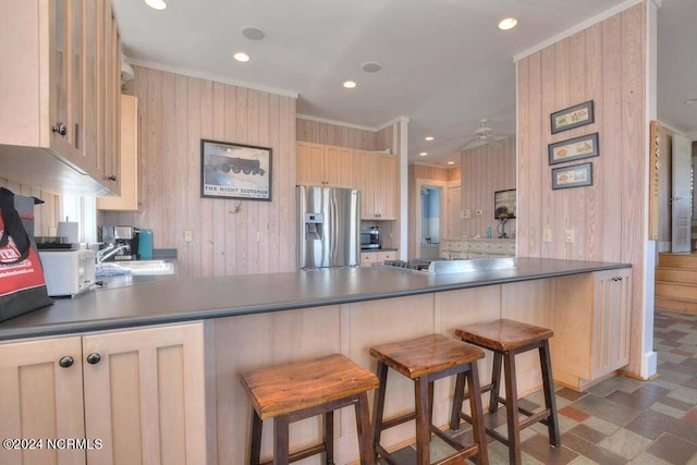 kitchen with light brown cabinets, kitchen peninsula, a kitchen breakfast bar, and stainless steel appliances