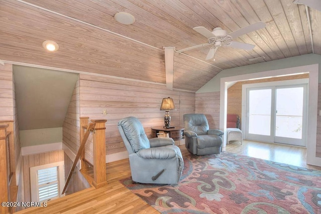 living area with wooden walls, wooden ceiling, lofted ceiling, and light wood-type flooring