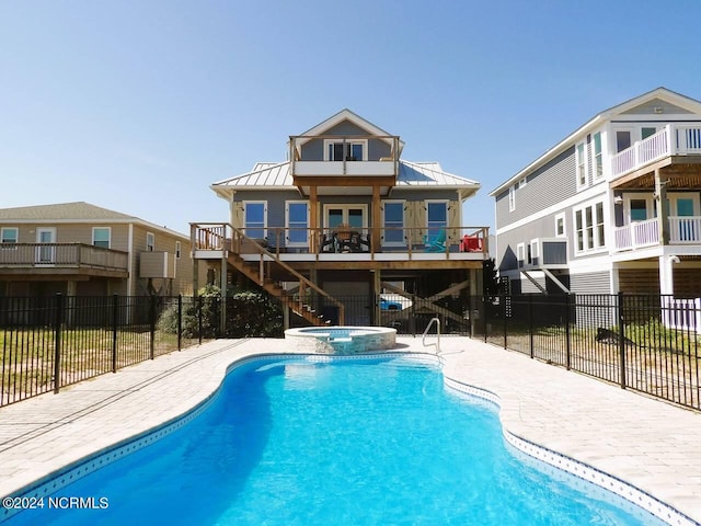 back of house featuring a balcony and a pool with hot tub