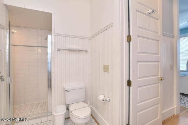 bathroom featuring tile patterned flooring, toilet, and an enclosed shower