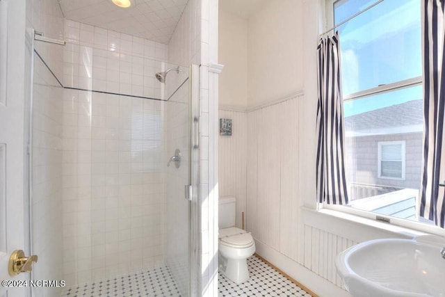 bathroom featuring tile patterned floors, tiled shower, sink, and toilet