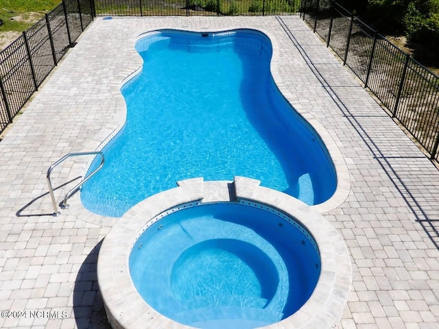 view of swimming pool featuring an in ground hot tub