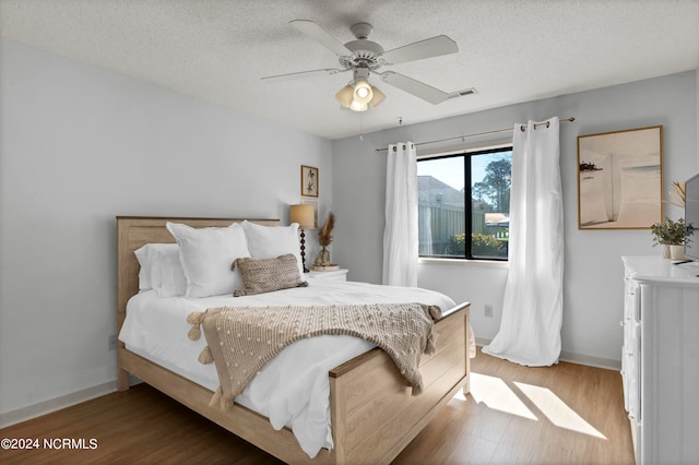 bedroom featuring ceiling fan, hardwood / wood-style flooring, and a textured ceiling