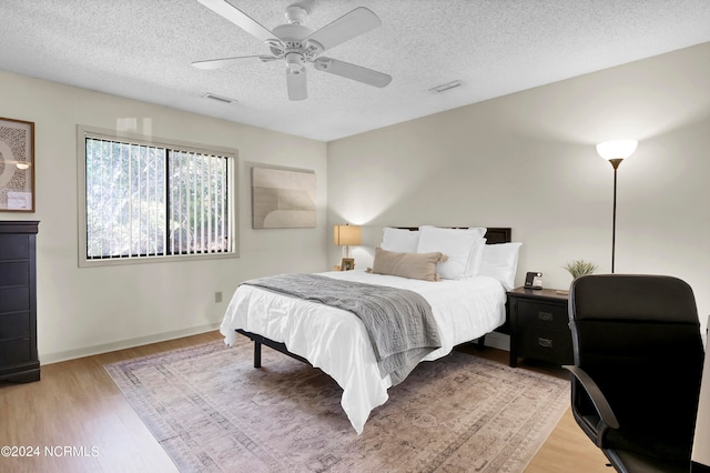 bedroom with light wood-type flooring, a textured ceiling, and ceiling fan