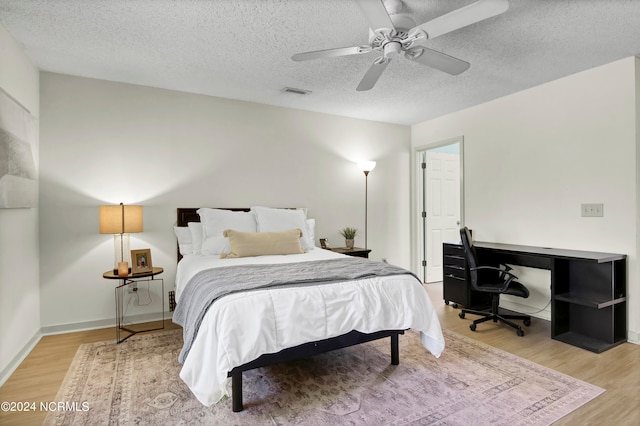 bedroom with light wood-type flooring, a textured ceiling, and ceiling fan