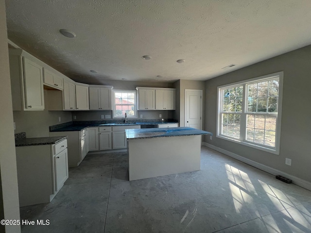 kitchen featuring sink, a textured ceiling, white cabinets, and a kitchen island