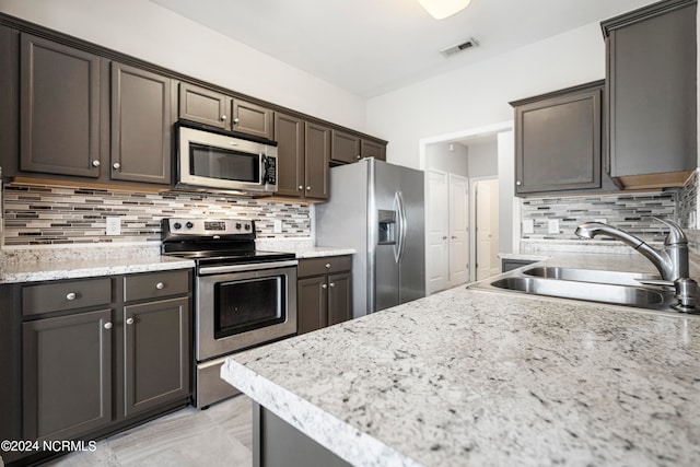 kitchen with dark brown cabinets, backsplash, appliances with stainless steel finishes, and sink