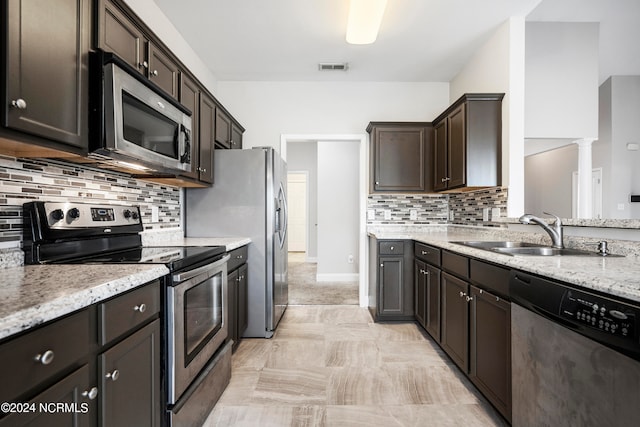 kitchen with light tile patterned floors, backsplash, stainless steel appliances, light stone countertops, and sink