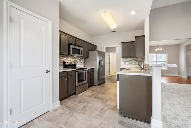 kitchen featuring light carpet, tasteful backsplash, kitchen peninsula, and stainless steel appliances