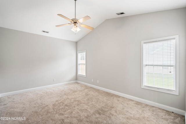 carpeted empty room with a wealth of natural light, ceiling fan, and vaulted ceiling