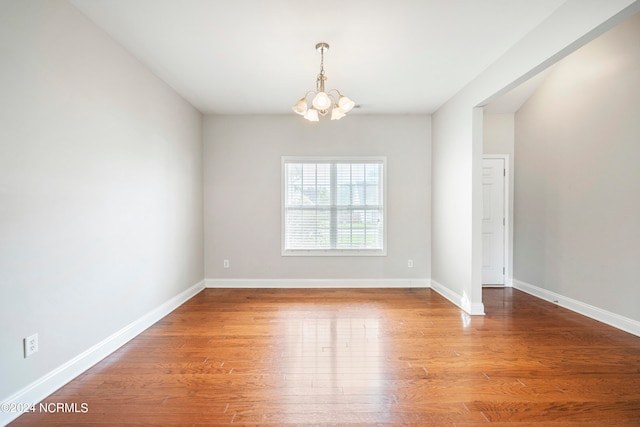 unfurnished room featuring wood-type flooring and a chandelier