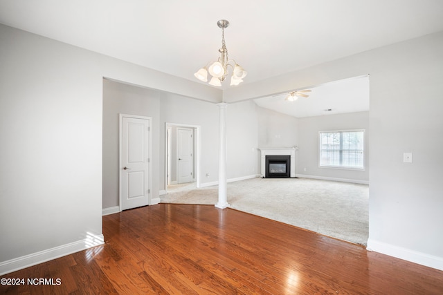 unfurnished living room with ceiling fan with notable chandelier and carpet flooring