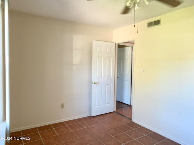 spare room with dark tile patterned flooring and ceiling fan