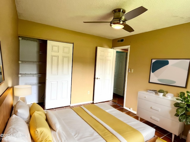 tiled bedroom with ceiling fan, a closet, and a textured ceiling