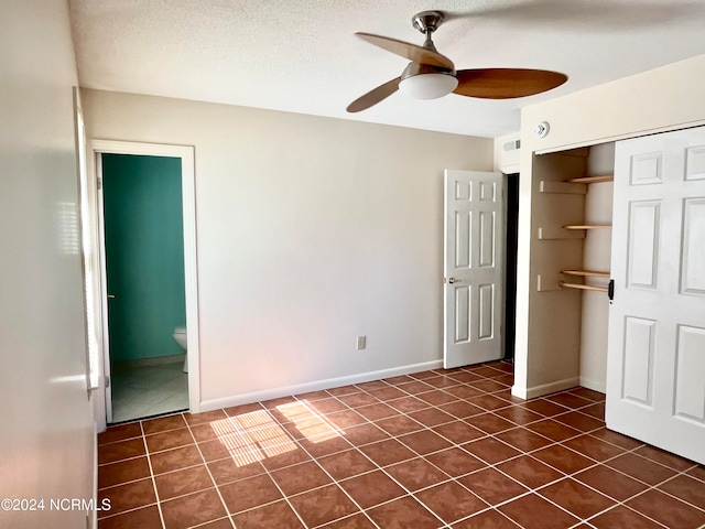 unfurnished bedroom featuring ceiling fan, a closet, dark tile patterned flooring, connected bathroom, and a textured ceiling