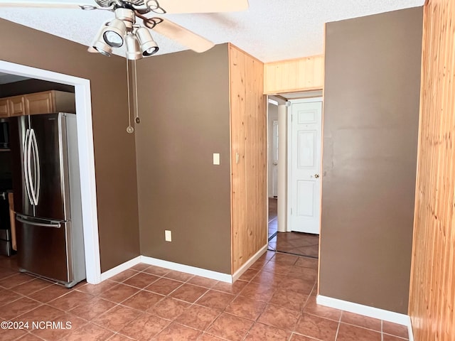 kitchen with wood walls, stainless steel fridge, ceiling fan, light brown cabinetry, and a textured ceiling