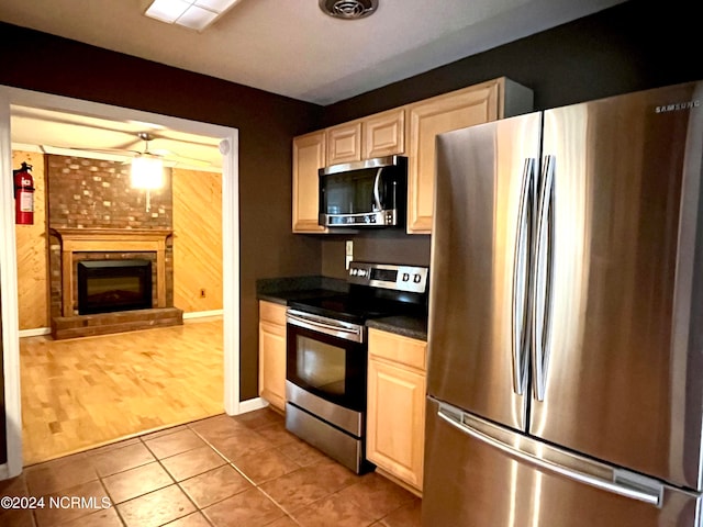 kitchen with stainless steel appliances, a fireplace, and light hardwood / wood-style flooring