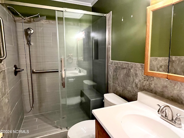 bathroom with vanity, a shower with door, tile walls, ornamental molding, and toilet