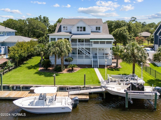 back of property with a water view and a lawn