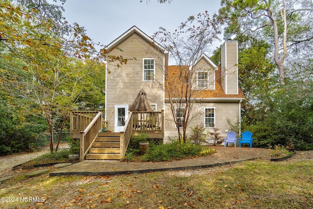 back of property with a chimney and a deck