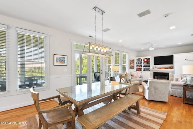 604 Currituck Way, Bald Head Island, NC 28461 - dining room featuring light wood-style flooring, a ceiling fan, a fireplace, wainscoting, and recessed lighting